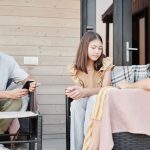 Família de três pessoas conversa seriamente reunida em um pátio ao ar livre.