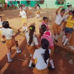 Estudantes de uniforme participam de atividades ao ar livre no pátio da escola.