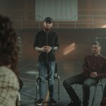 Grupo diverso de pessoas sentadas em círculo durante uma sessão de apoio e conversa sobre saúde mental.