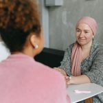 Duas mulheres compartilham um momento de apoio e acolhimento em um ambiente interno.