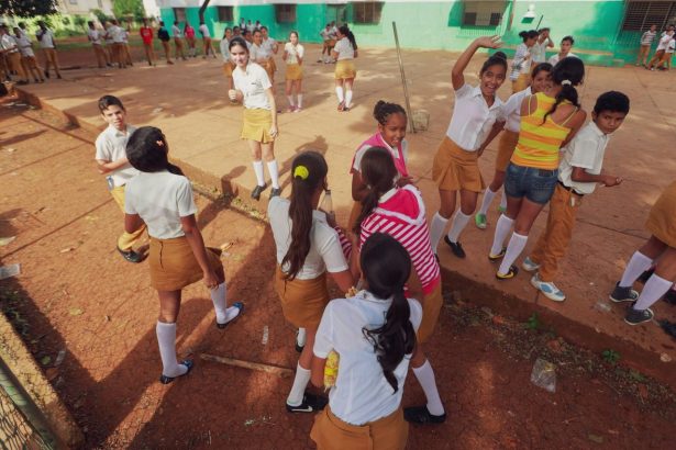 Estudantes de uniforme participam de atividades ao ar livre no pátio da escola.