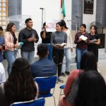 Jovens participam de uma atividade religiosa em uma igreja, acompanhando a celebração e fazendo leituras.