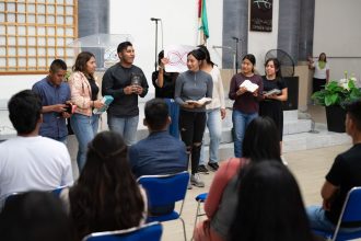 Jovens participam de uma atividade religiosa em uma igreja, acompanhando a celebração e fazendo leituras.