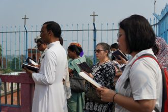 Grupo diverso de pessoas participa de uma oração ao ar livre, em Chinsurah, na Índia.
